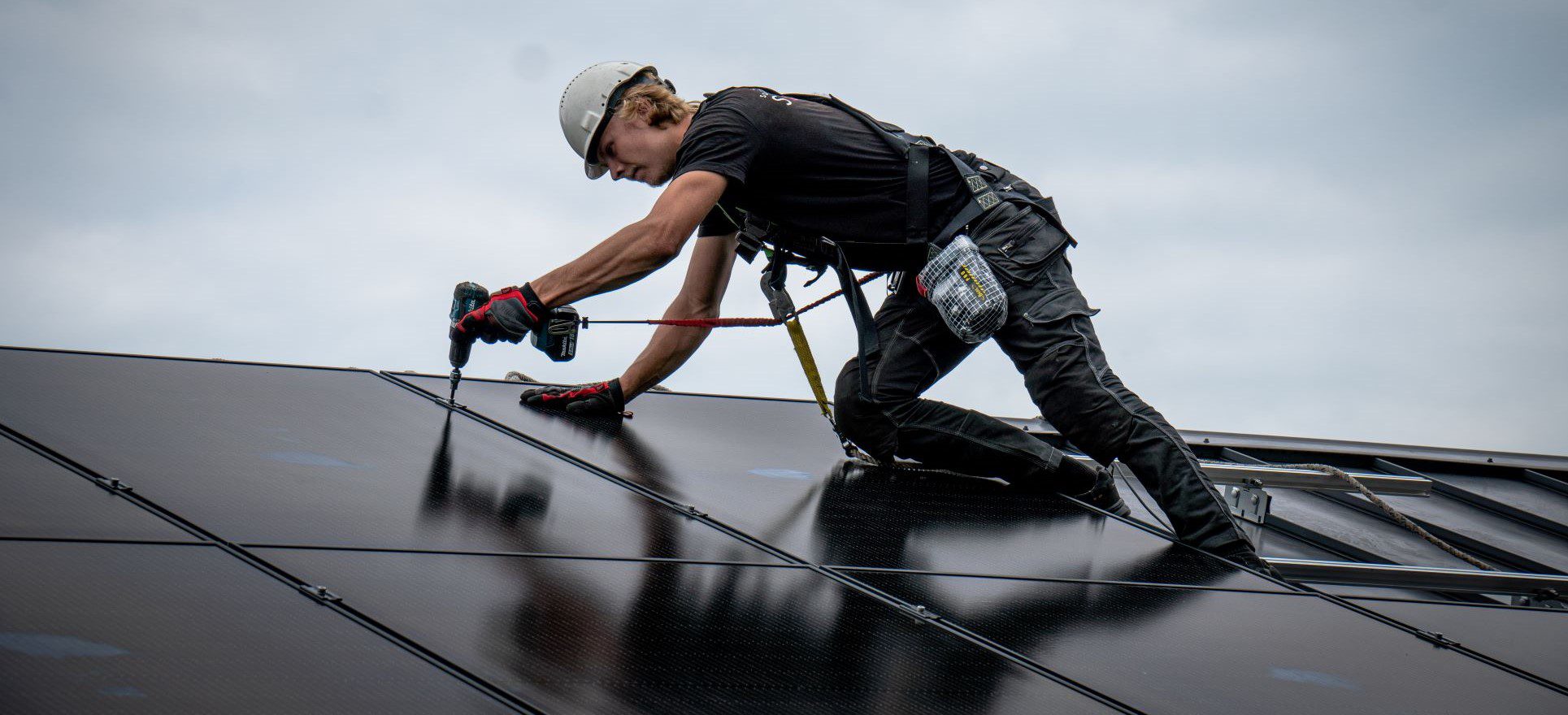 Asentaja kiinnittämässä aurinkopaneelia katolle